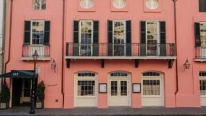 restaurant exterior with a pink facade, balcony, french doors