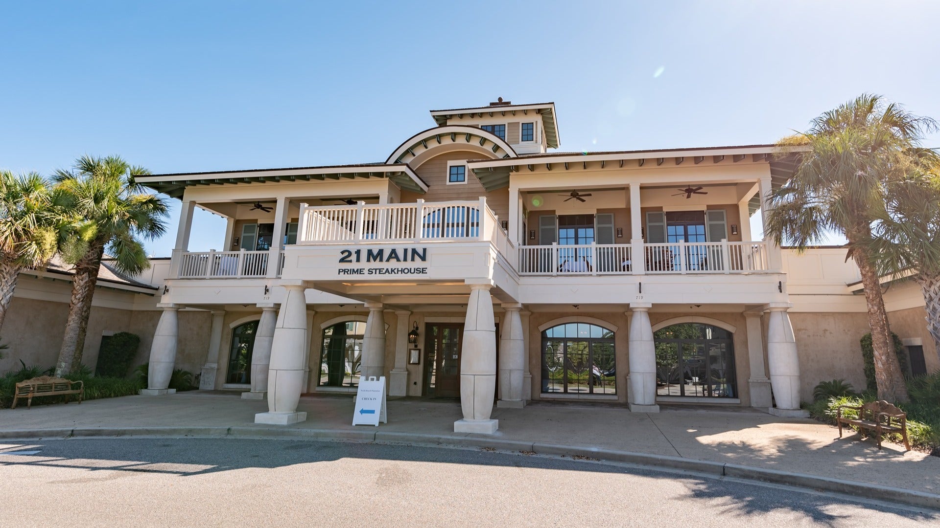 restaurant exterior with palm trees and a driveway