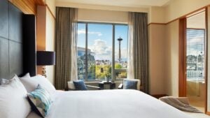 hotel bedroom with bed, chairs, lamp, view of seattle in the window