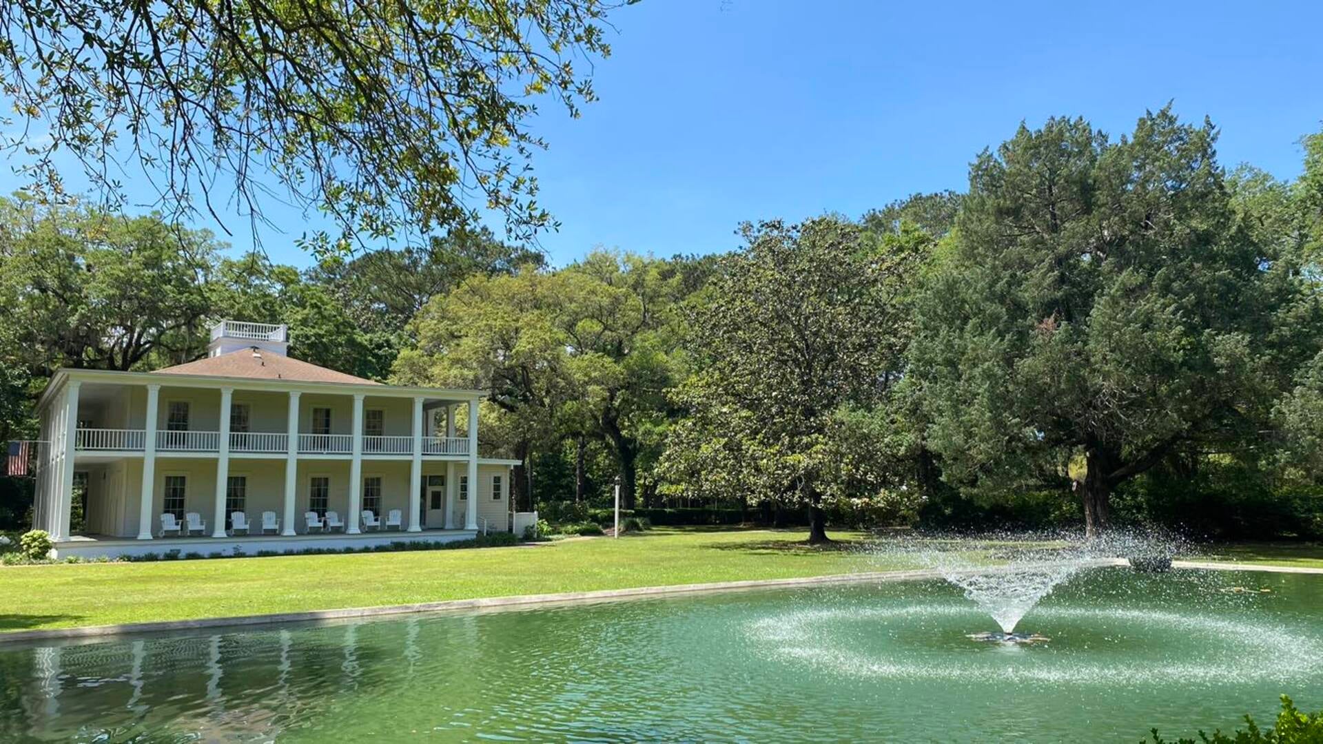 house with a fountain in front and trees at the back