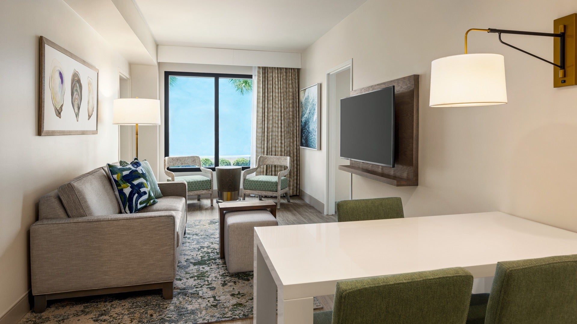 hotel room with dining table, chairs, couch, TV, and wall lamps