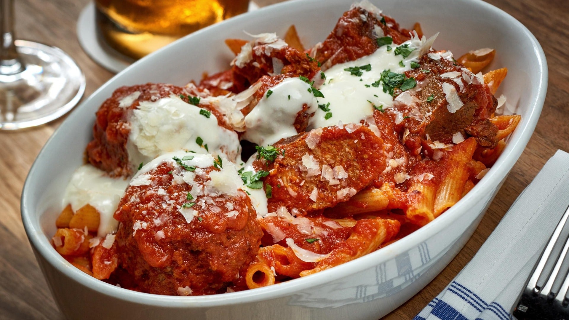 pasta dish on a plate with a fork and drinks on the side