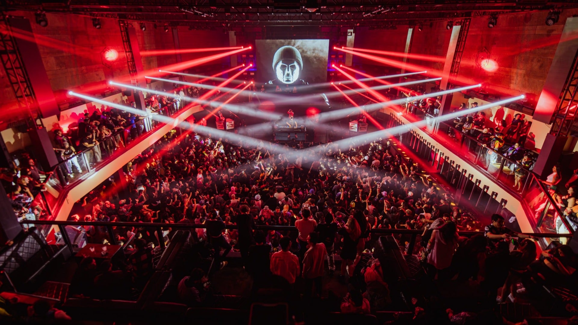 people dancing in a nightclub with a dj, lights and screen