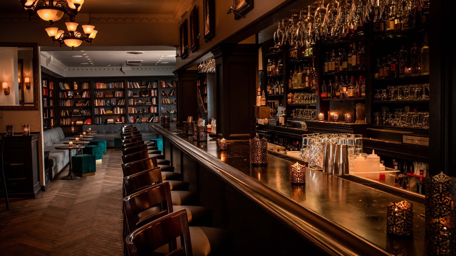 restaurant bar with stools, alcohol on shelves and books at the back