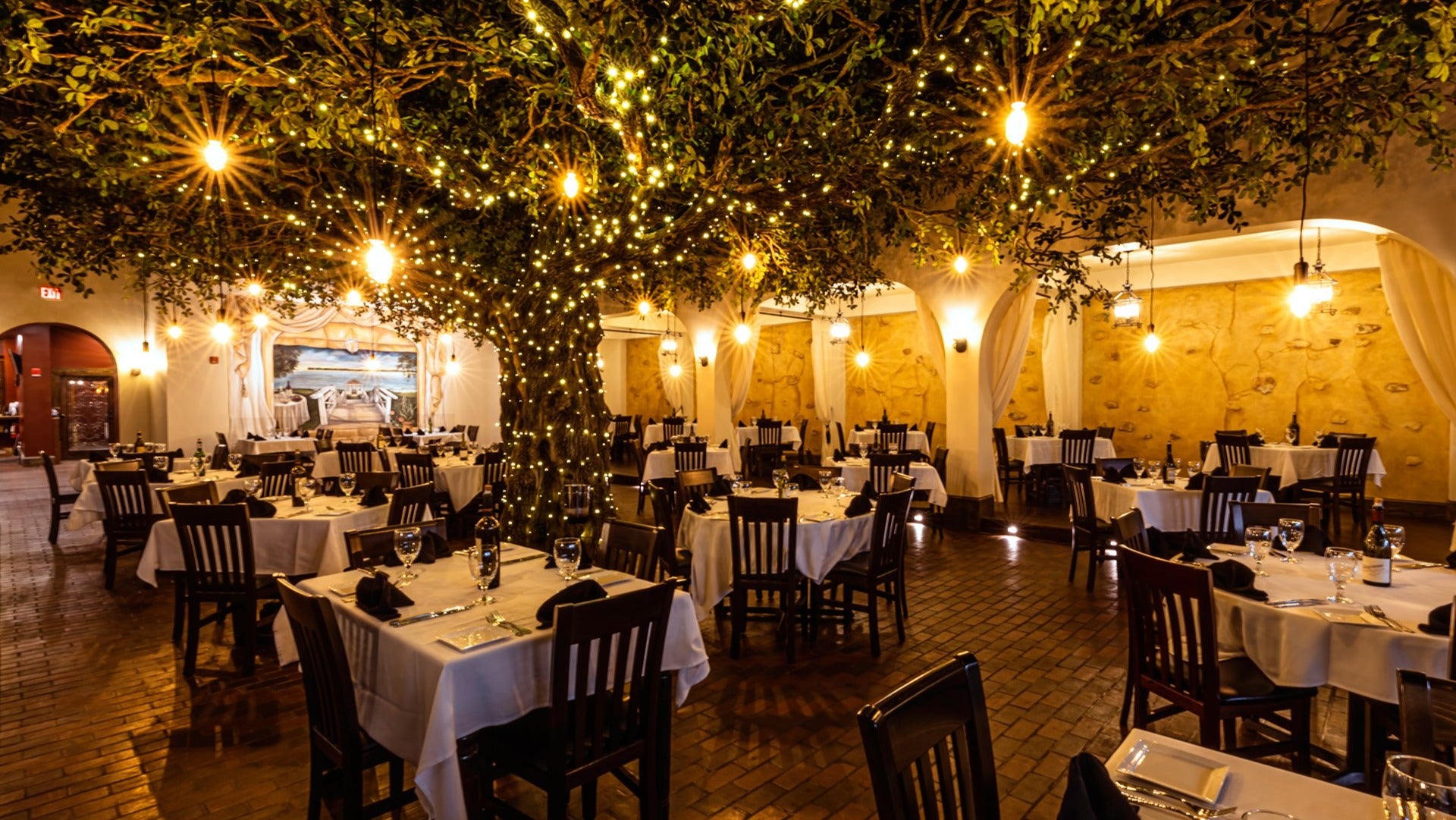 dining tables and chairs with tree with lots of lights