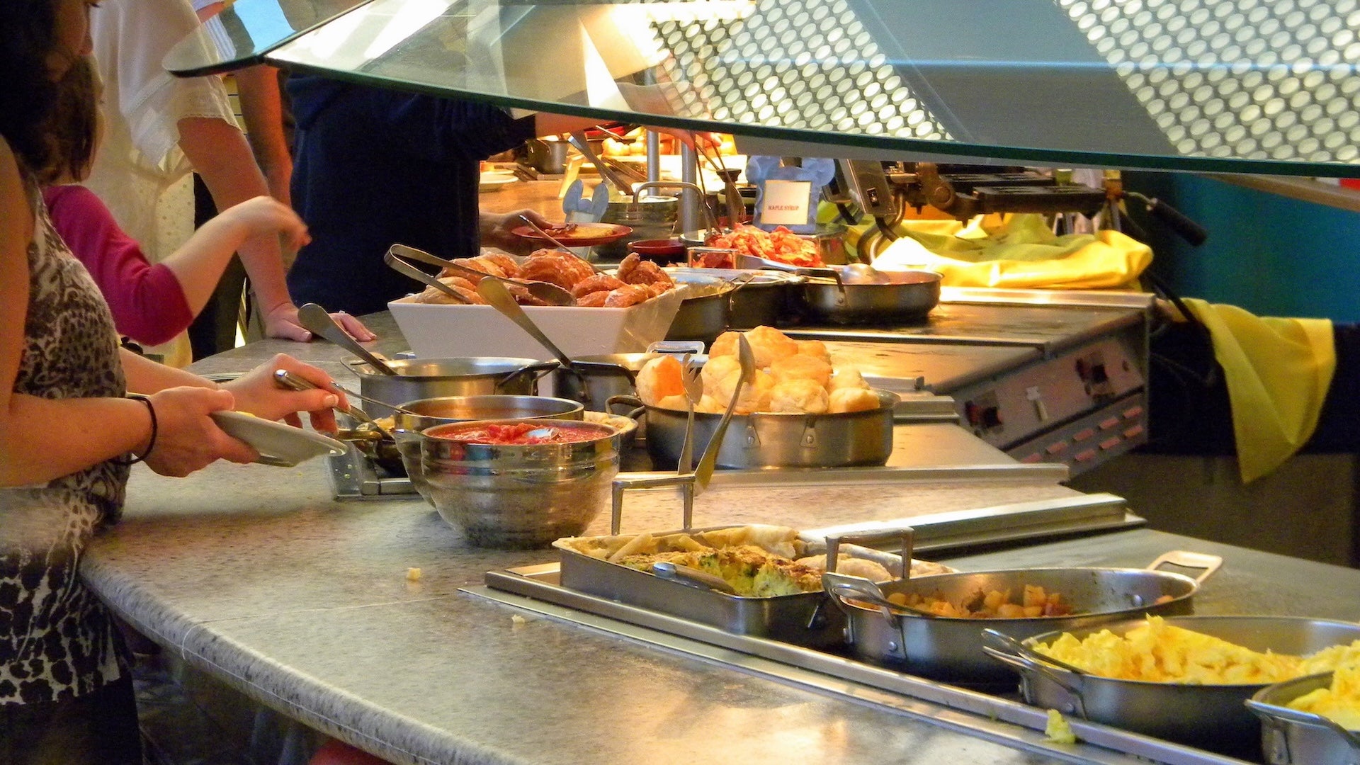 a woman getting food in a buffet