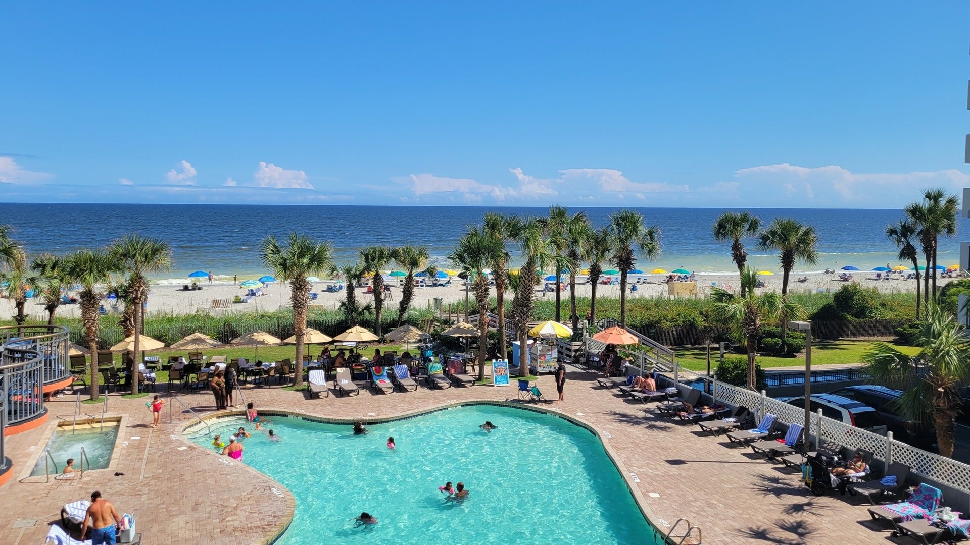 people enjoying in a pool with pool chairs and cabanas and the ocean at the back