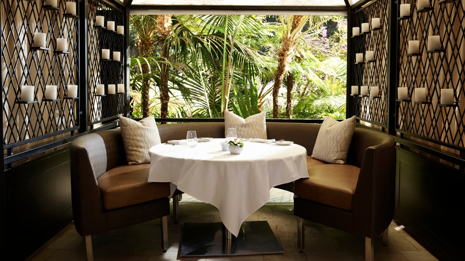 private dining table with candles on the walls and trees in the window