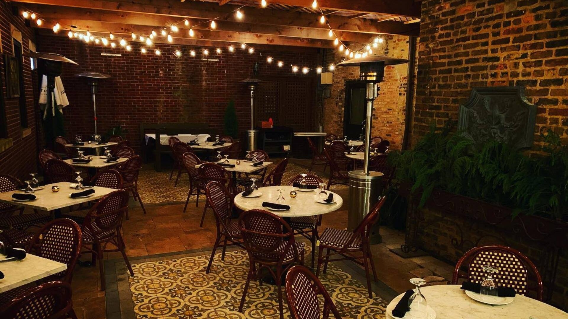 dining tables and chairs with twinkling lights and brick walls