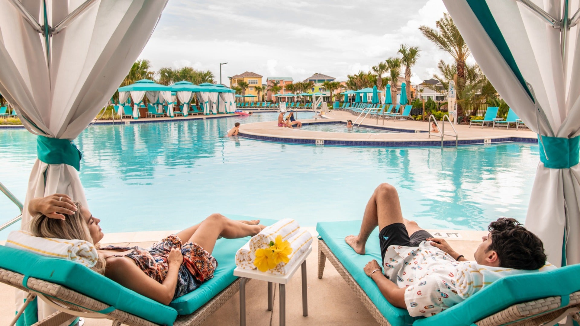 couple enjoying the pool with cabanas at the back