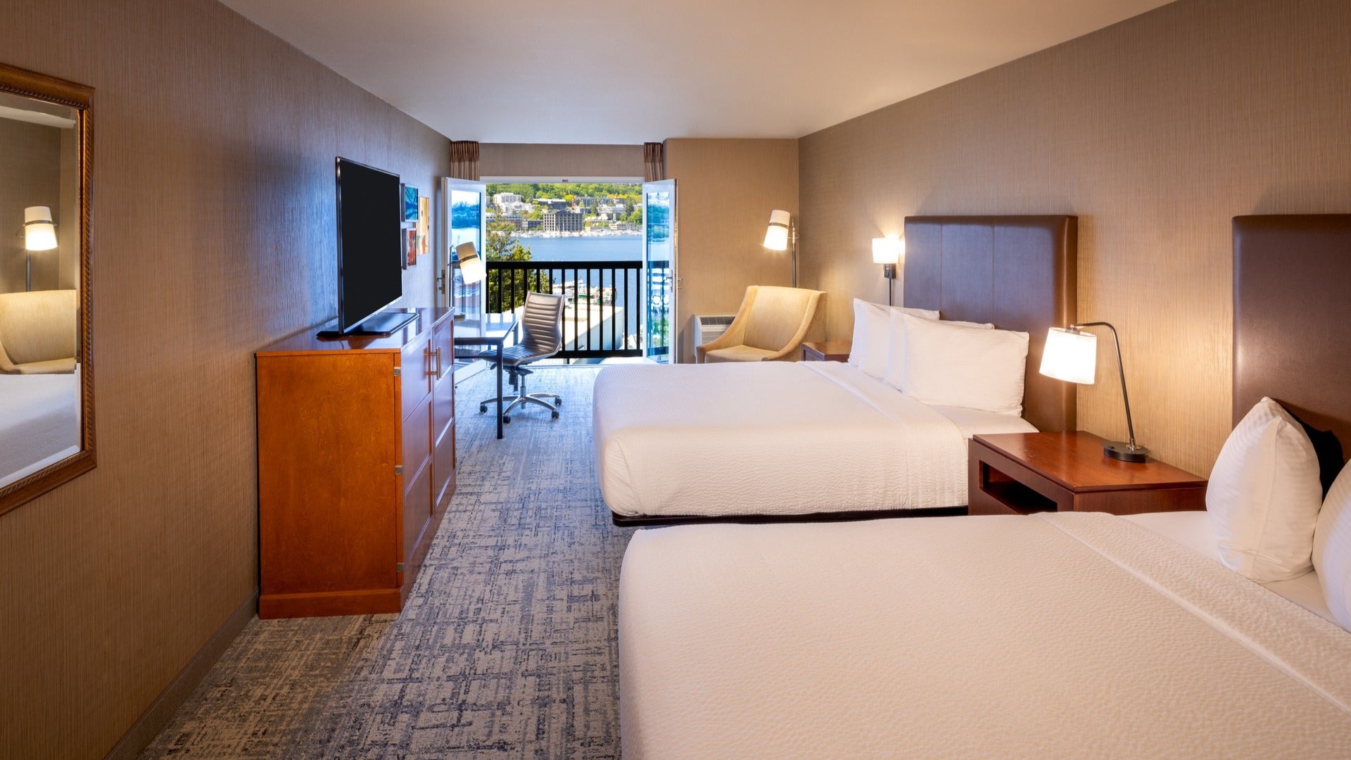 hotel beds with tv, lamps, chairs, balcony and view of lake union