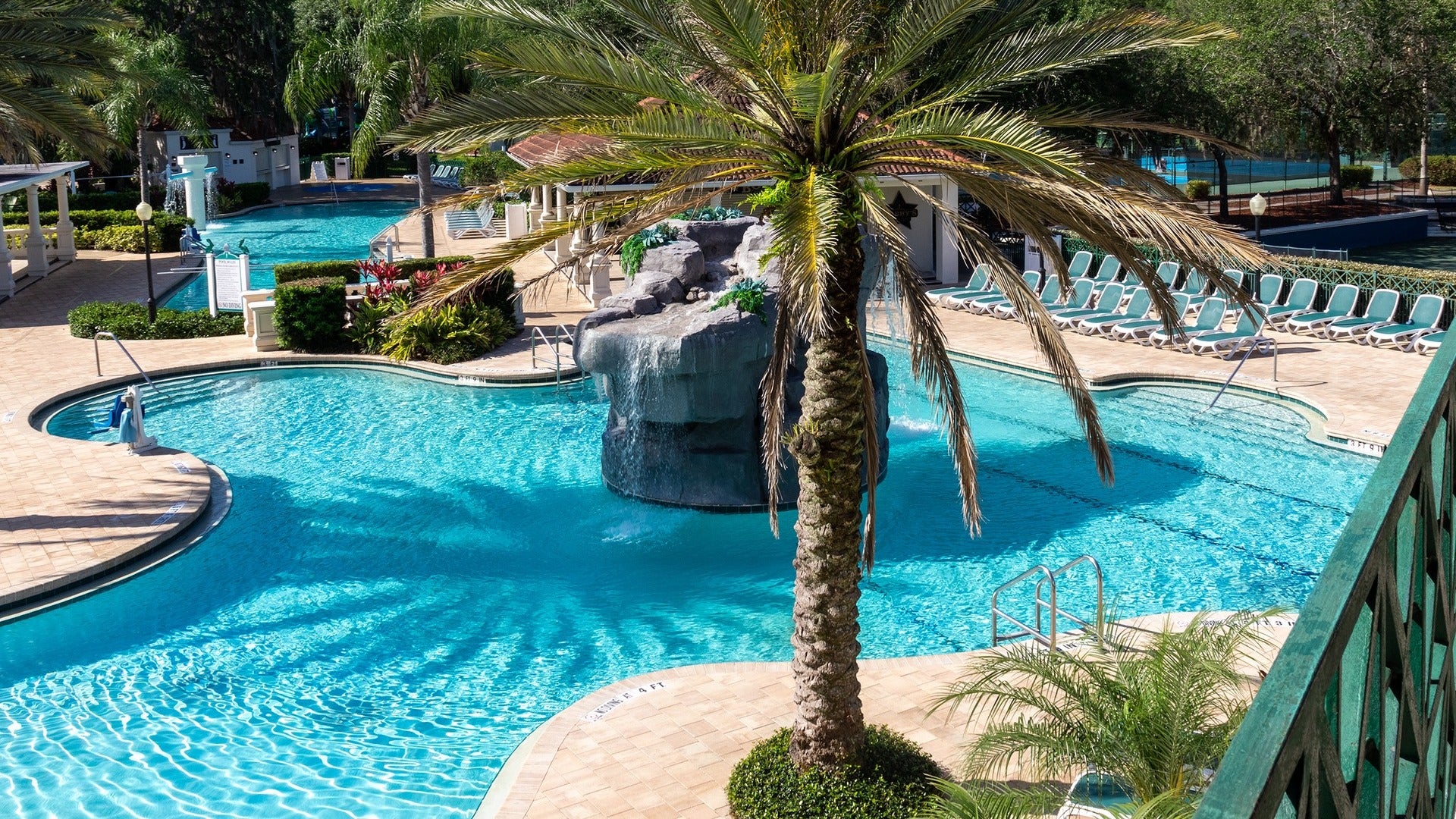 hotel pool with chairs, fountain and palm tree