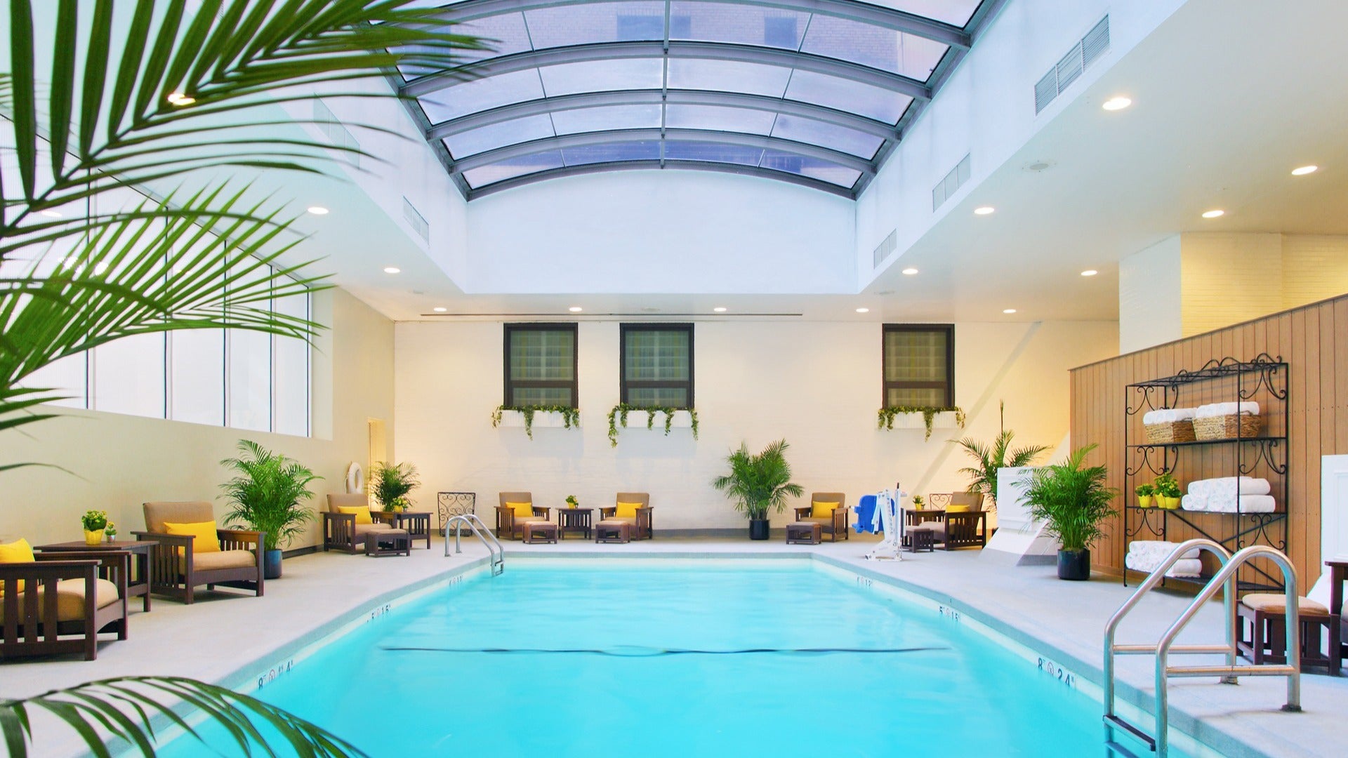 indoor pool with chairs, towels, plants