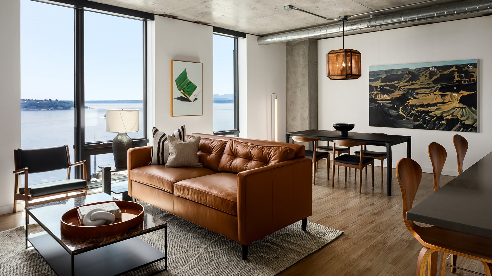 hotel room with couch, dining table, lamp, big windows