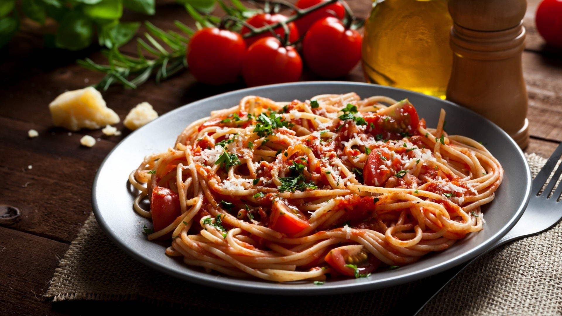 pasta dish with a fork and tomatoes at the back