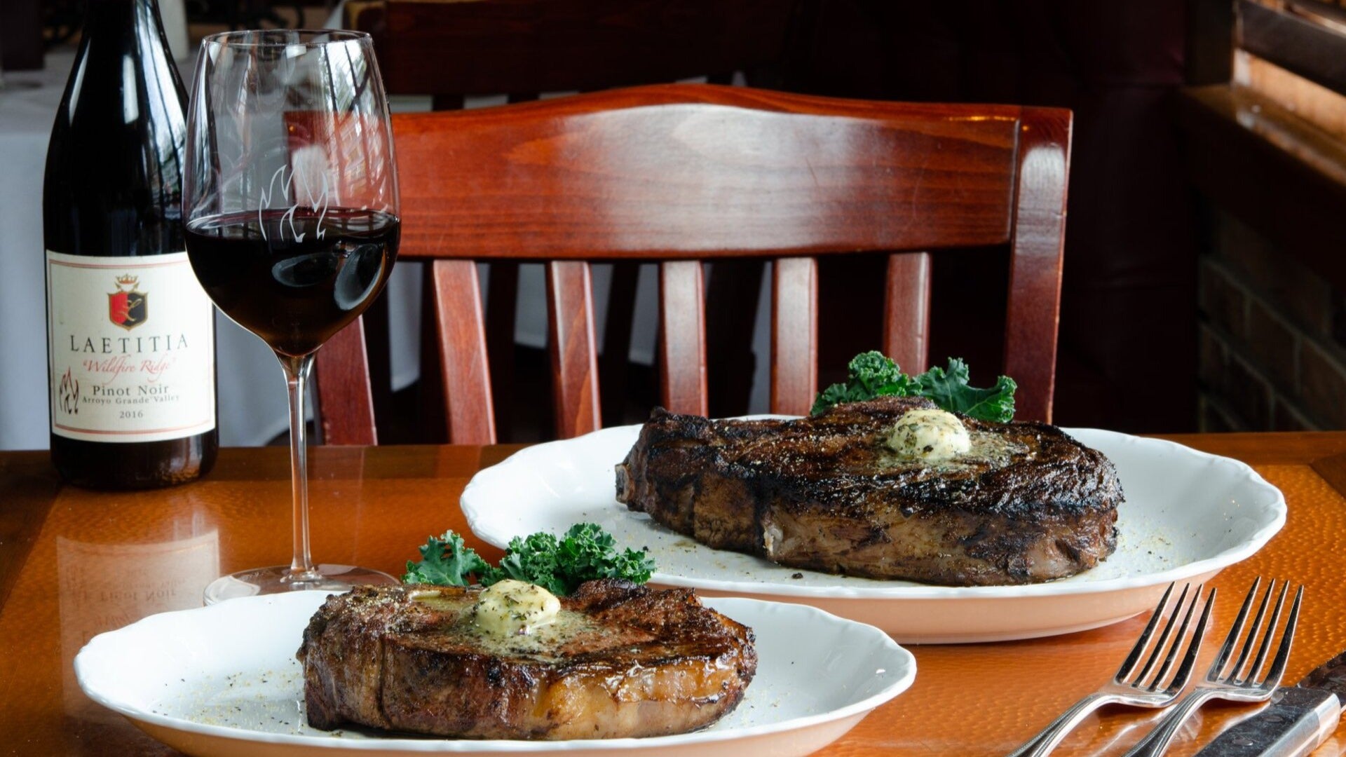 steaks served on plates with wine at the side