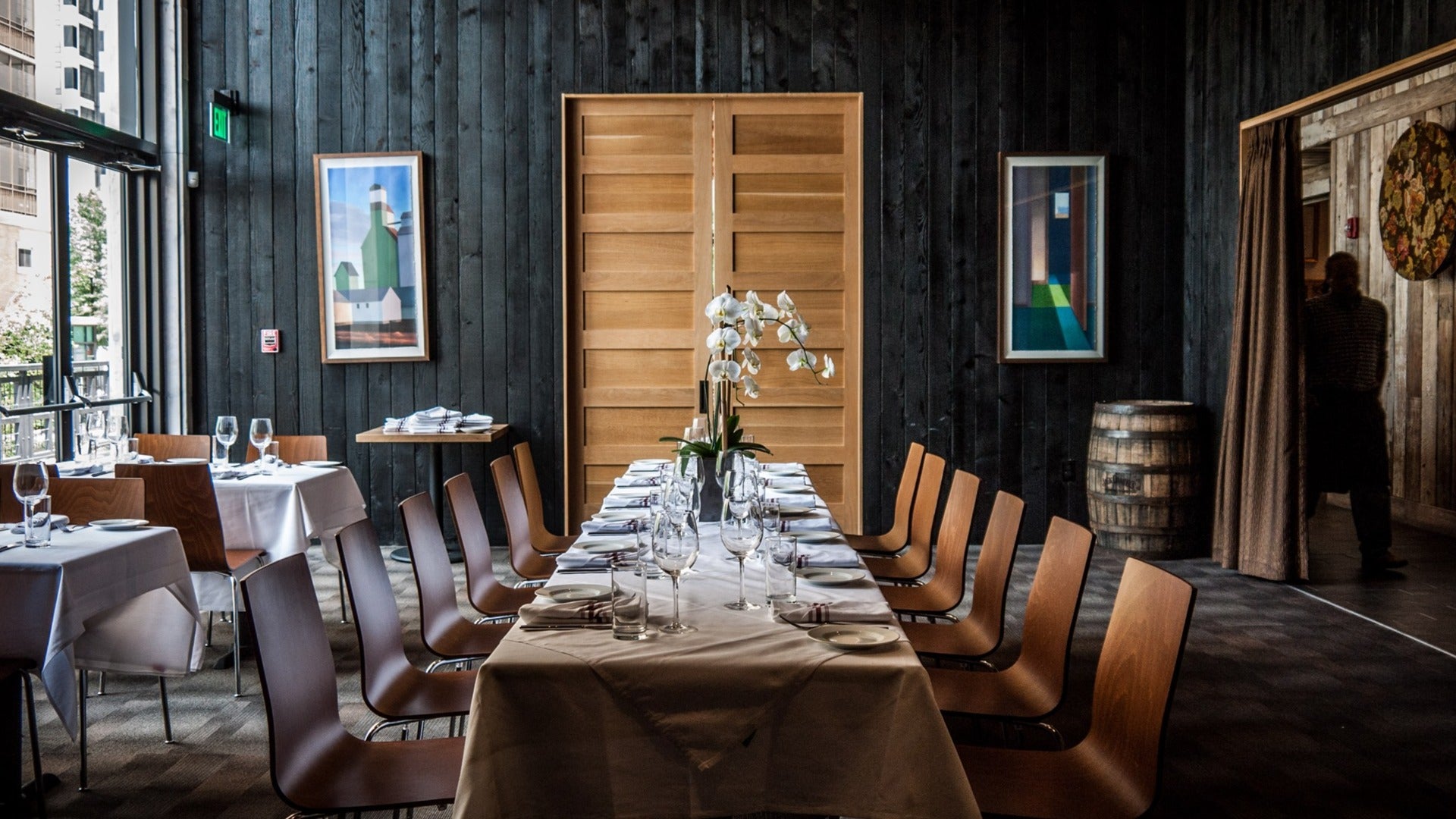 restaurant interior with long table, chairs, door at the back and barrel at the side