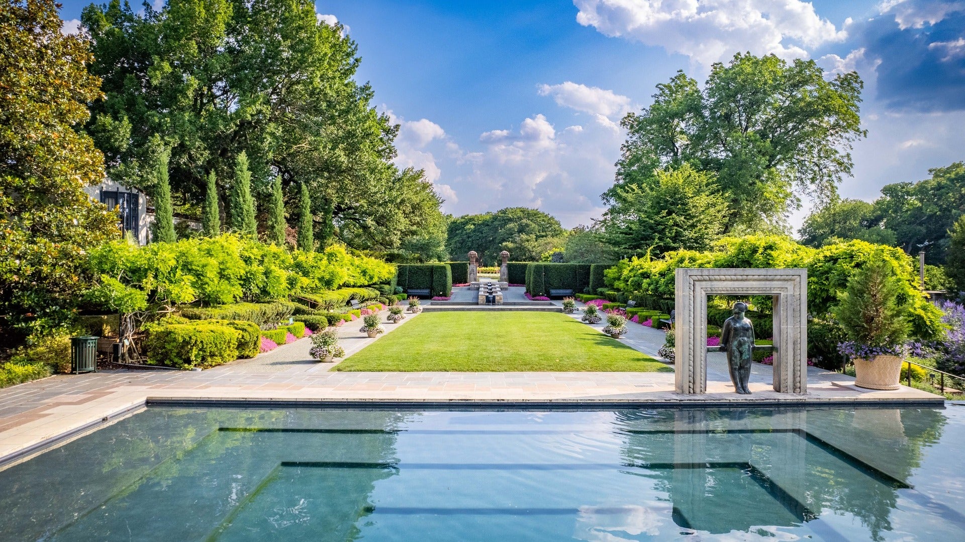 pond with statue and garden at the back with flowers and trees