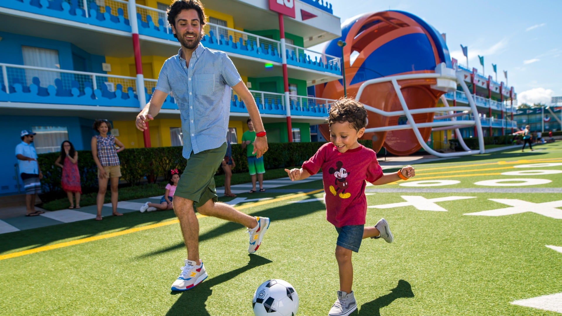 father and son kicking a soccer ball, resort has a giant helmet display