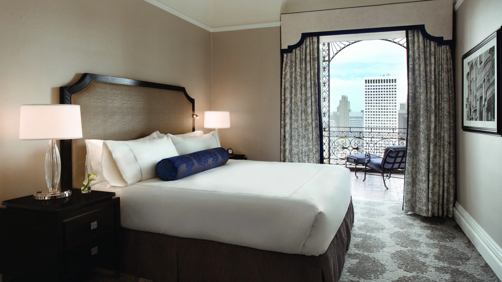 hotel room with bed, lamp, and balcony with city views