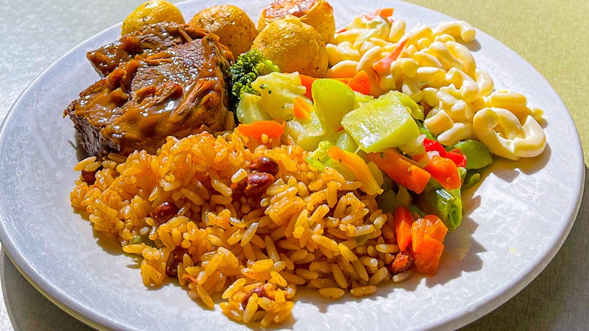 food plate with steak, macaroni, veggies, and rice