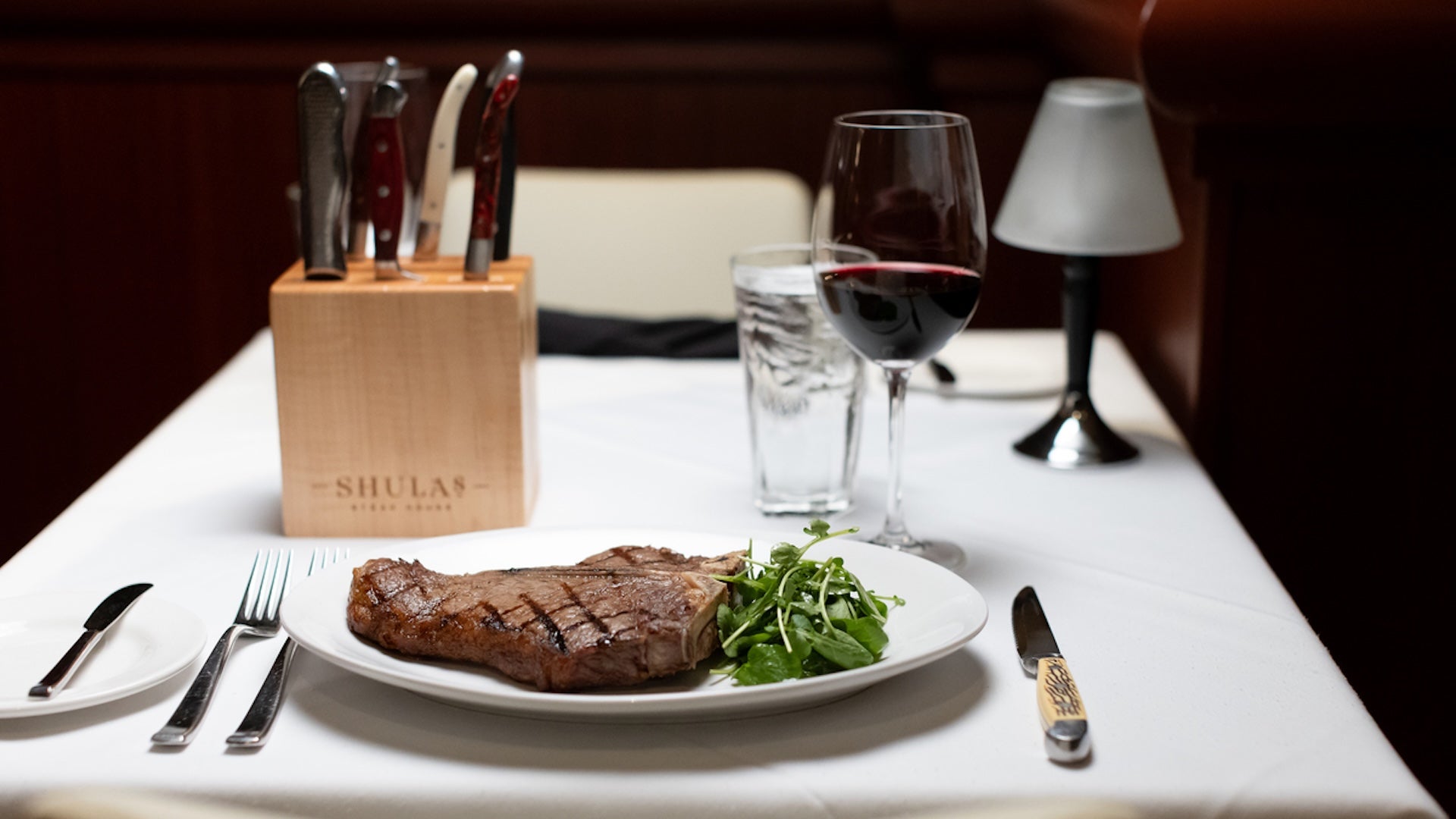 table setting with steak and a glass of wine