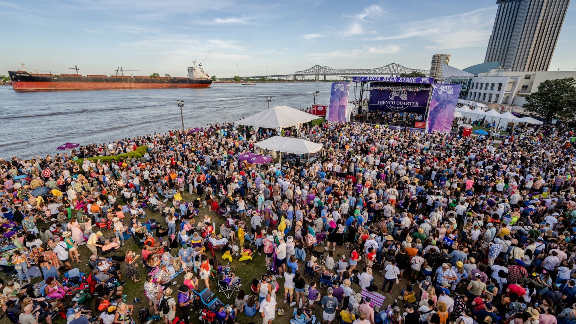 crowd watching a band with view of river and steamboat at the back