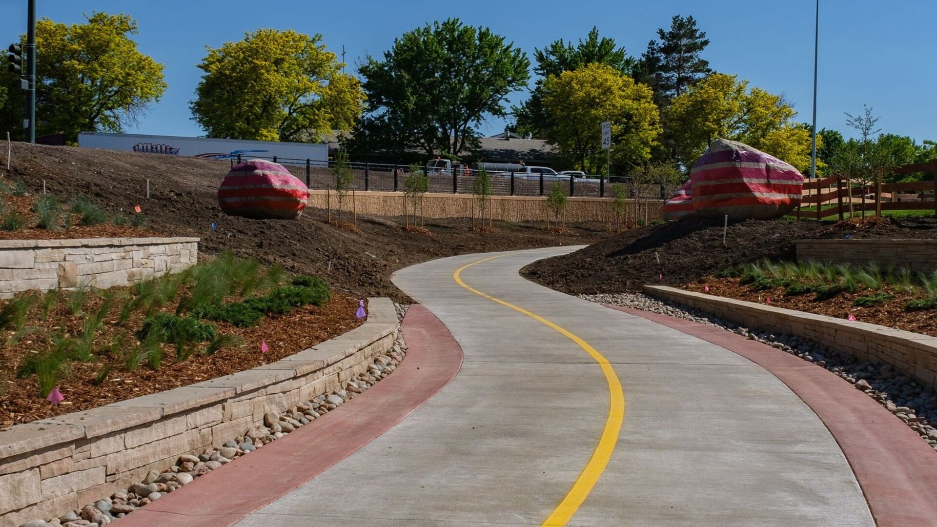 walking trail with boulders and cars parked atop