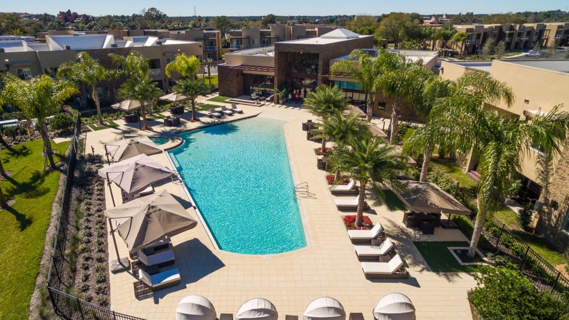 hotel with pool, pool lounges, palm trees and buildings at the back