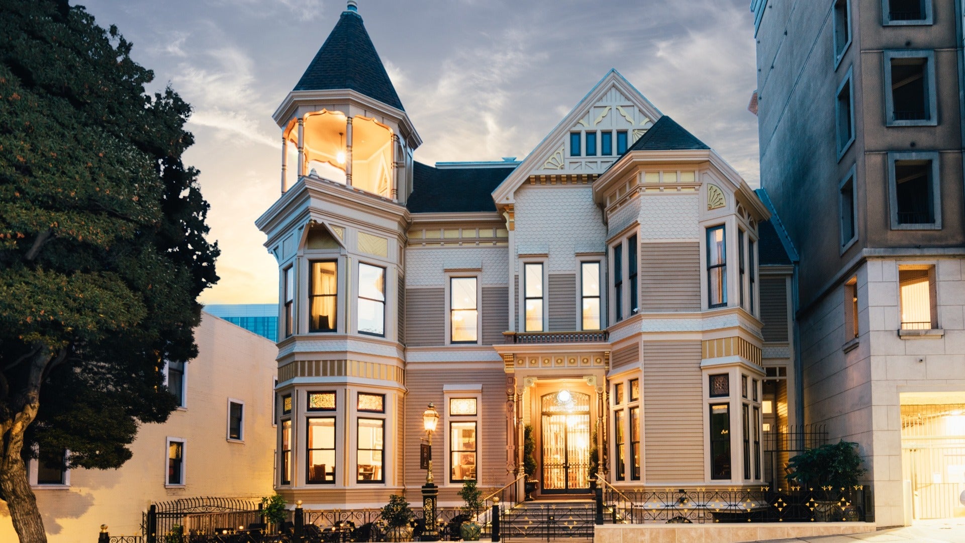 victorian style mansion with gate in front and tree