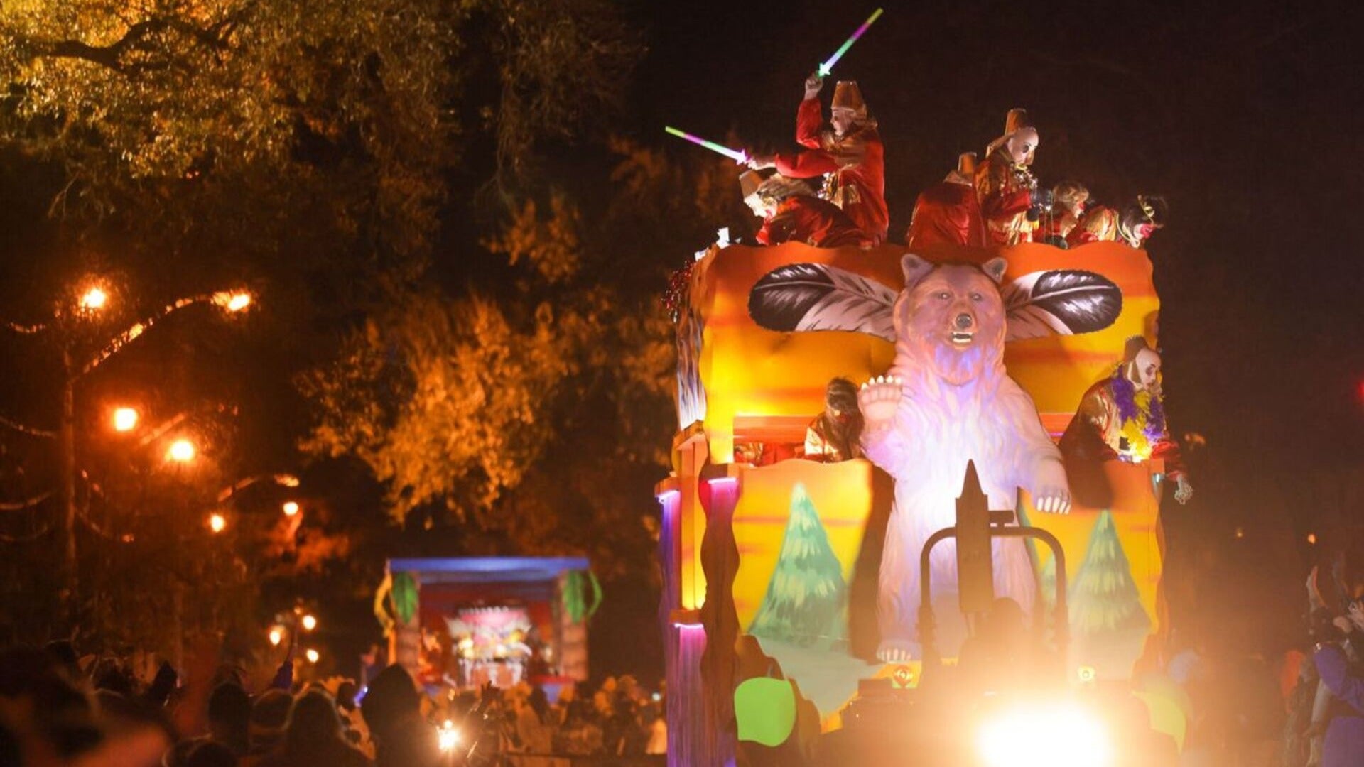 people in costumes riding a parade float with a bear in front