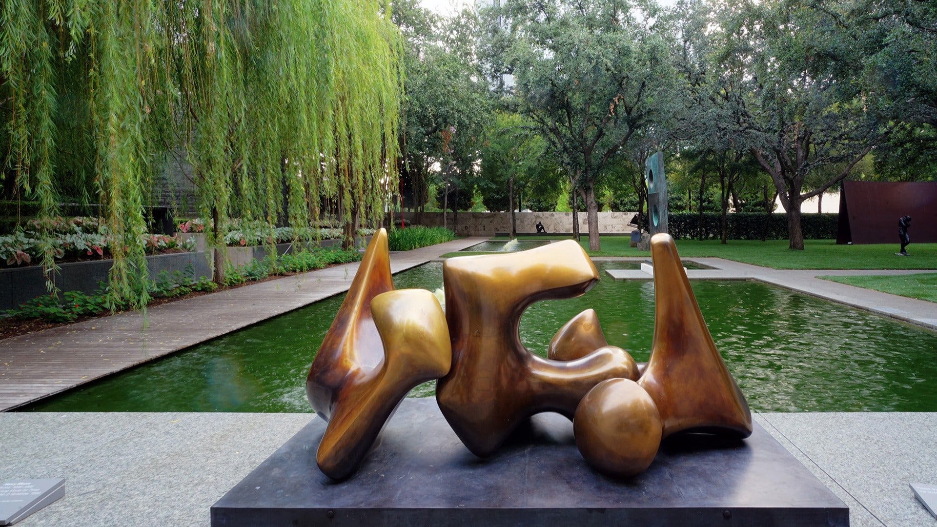 sculpture beside a water feature, surrounded by trees