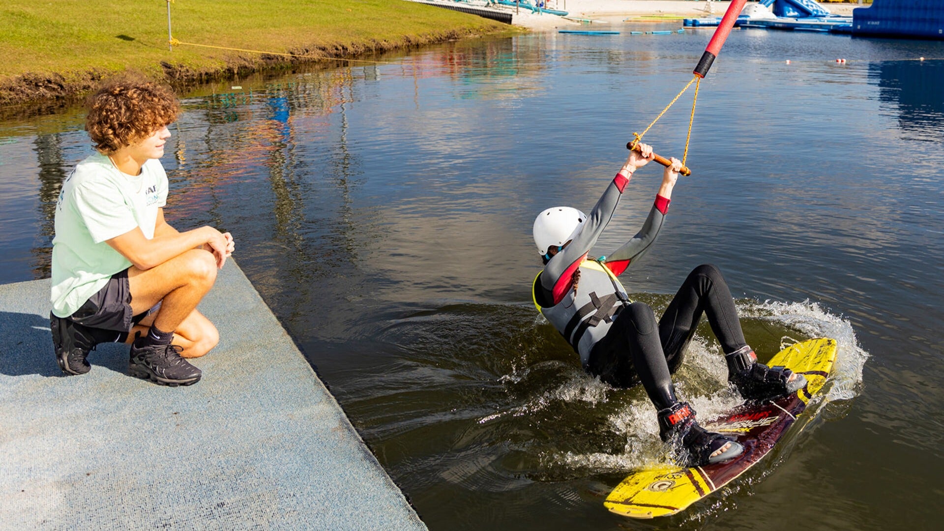 someone wakeboarding with an instructor in a water park