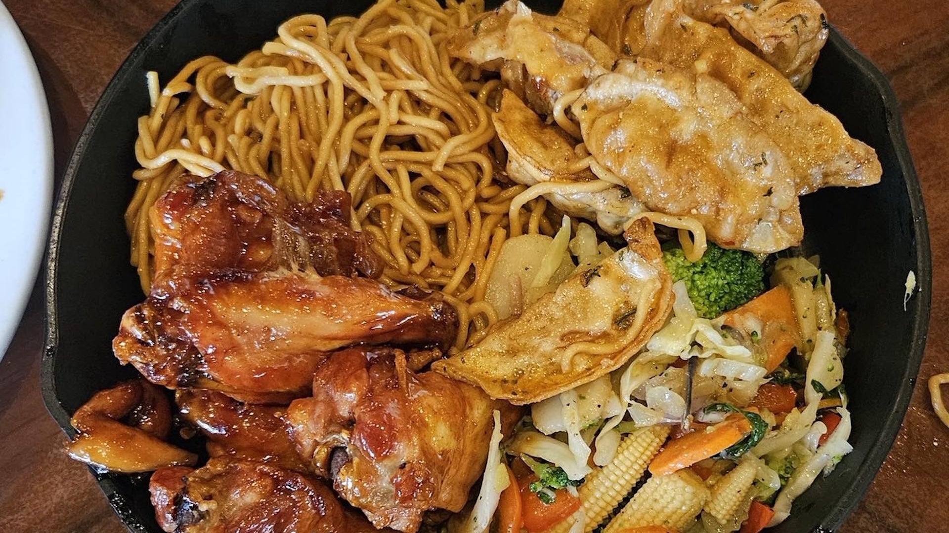 a plate with noodles, chicken, veggies and dumplings