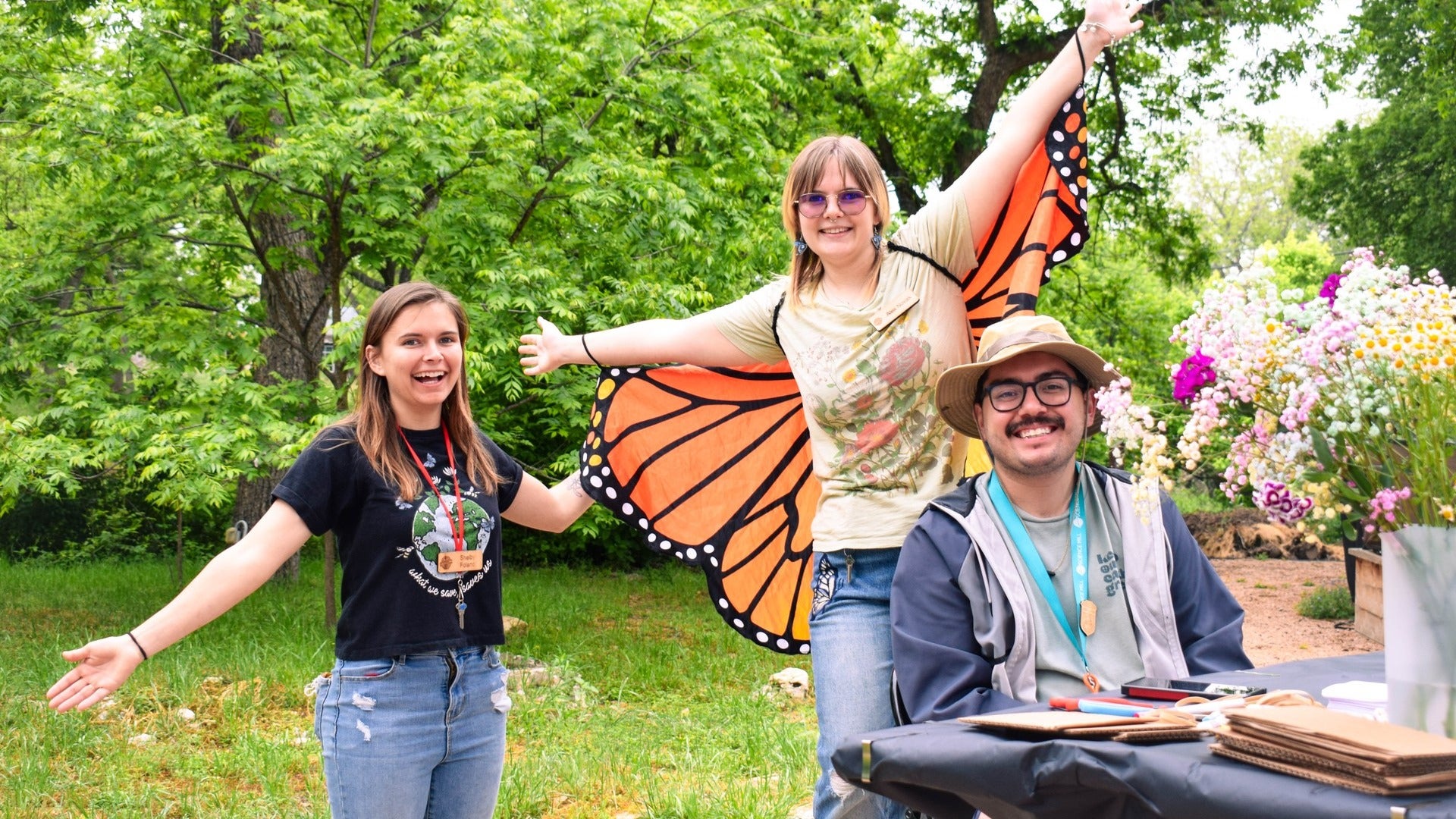 children having fun, wearing butterfly wings, flowers at the side