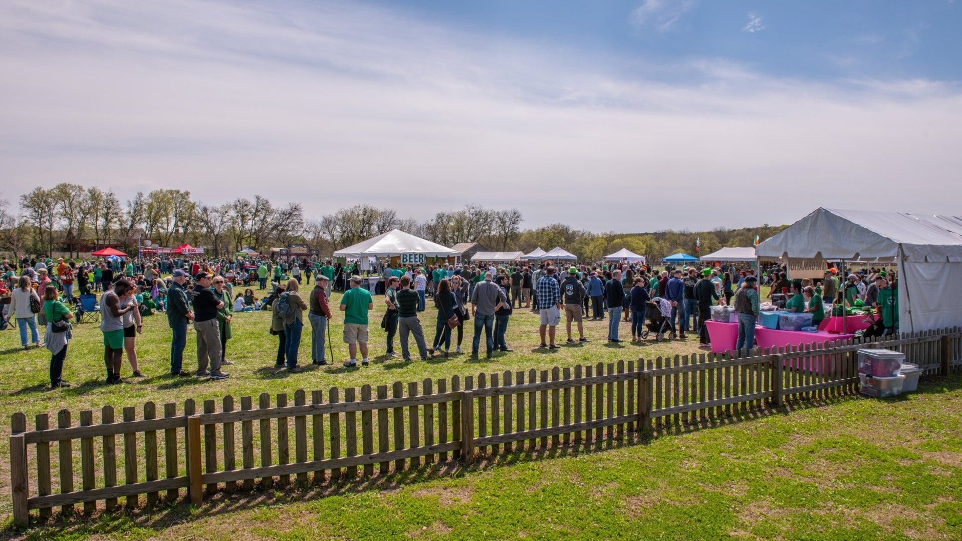 people celebrating st patricks day, beer stand and food stands around