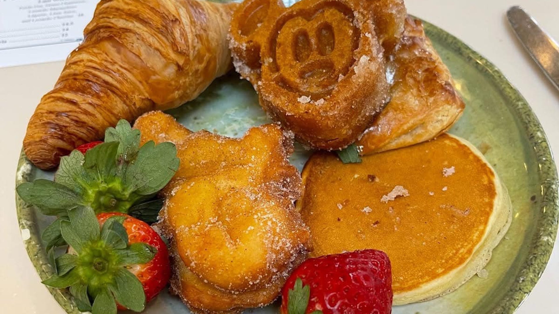 food plate with croissant, pancake, and strawberries