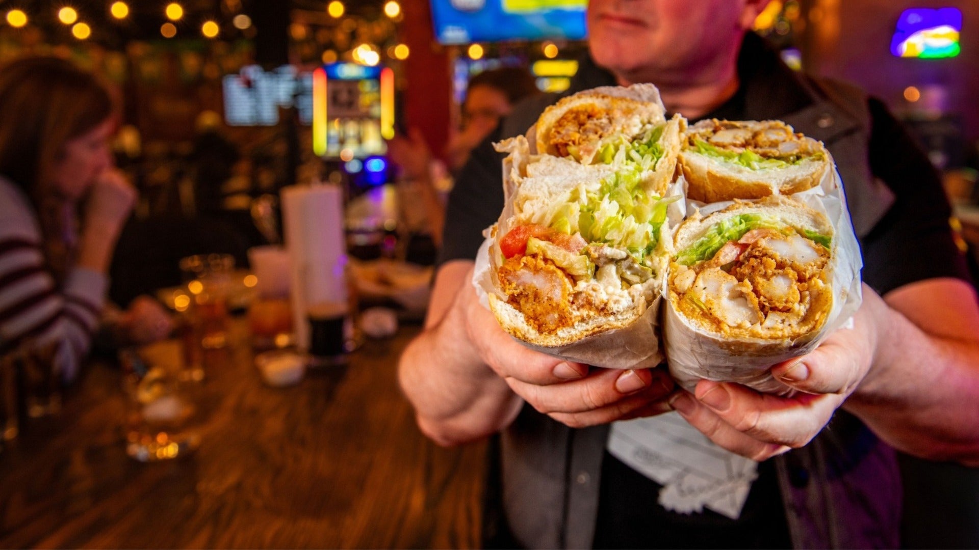 man holding a sandwich with other customers at the back