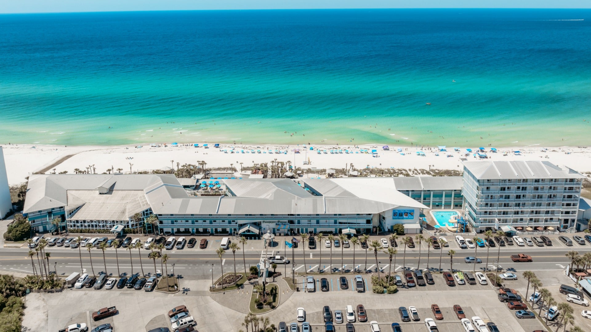 line of hotels with parking area and beach in front