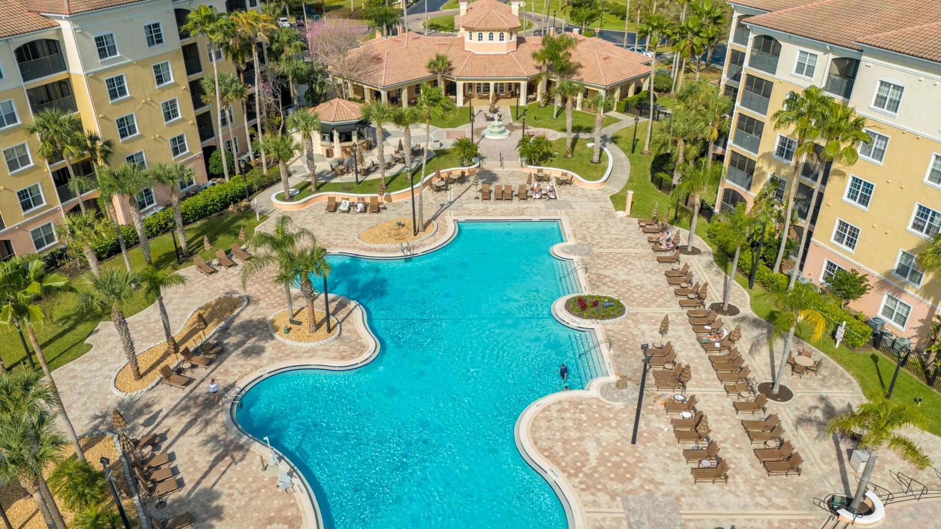 hotel or resort with pool in front, surrounded by trees and pool chairs