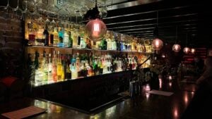 Dimly lit bar with back lit bottles in a speakeasy