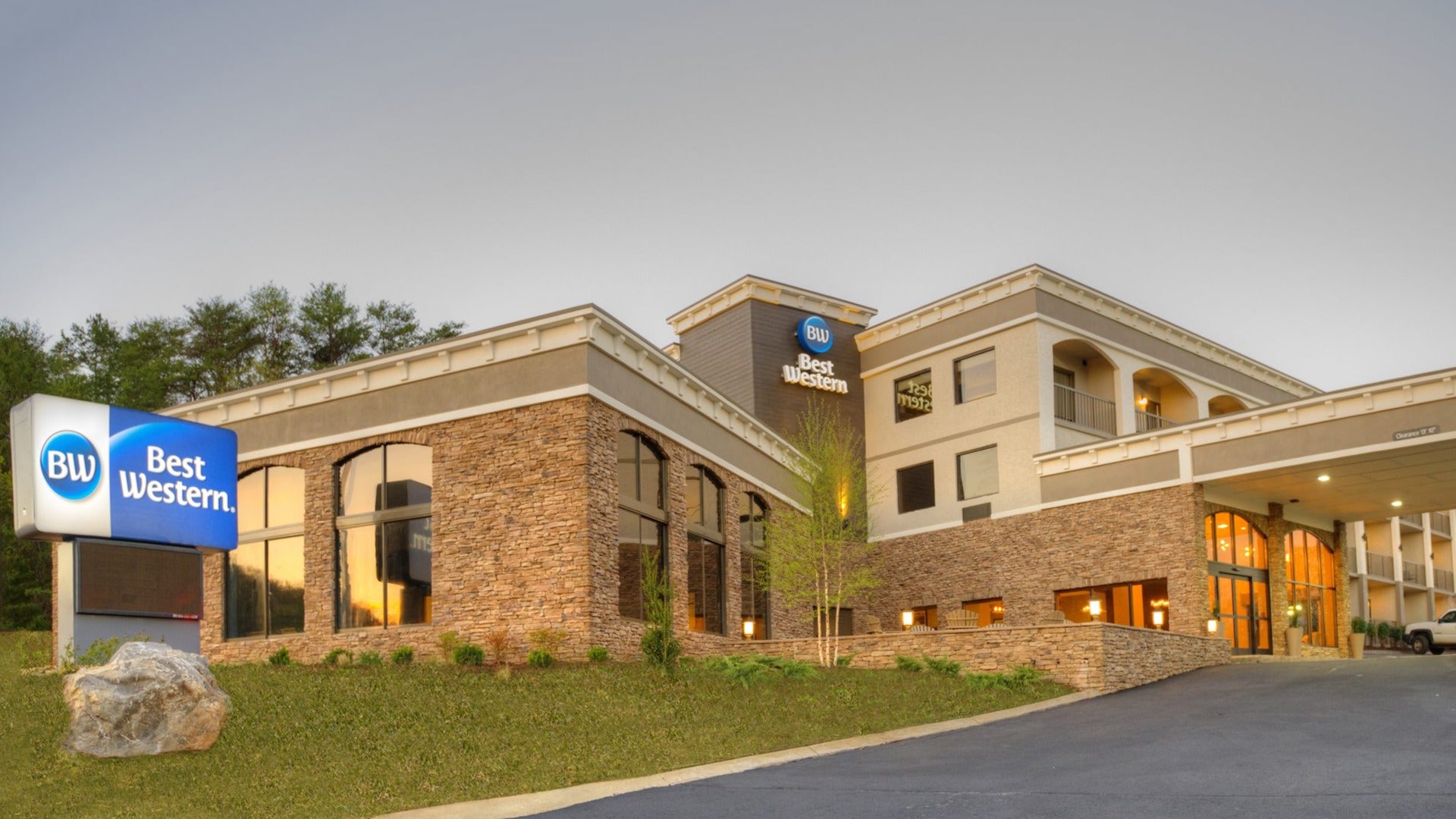 hotel exterior with signage, car by the entrance, brick walls and large windows