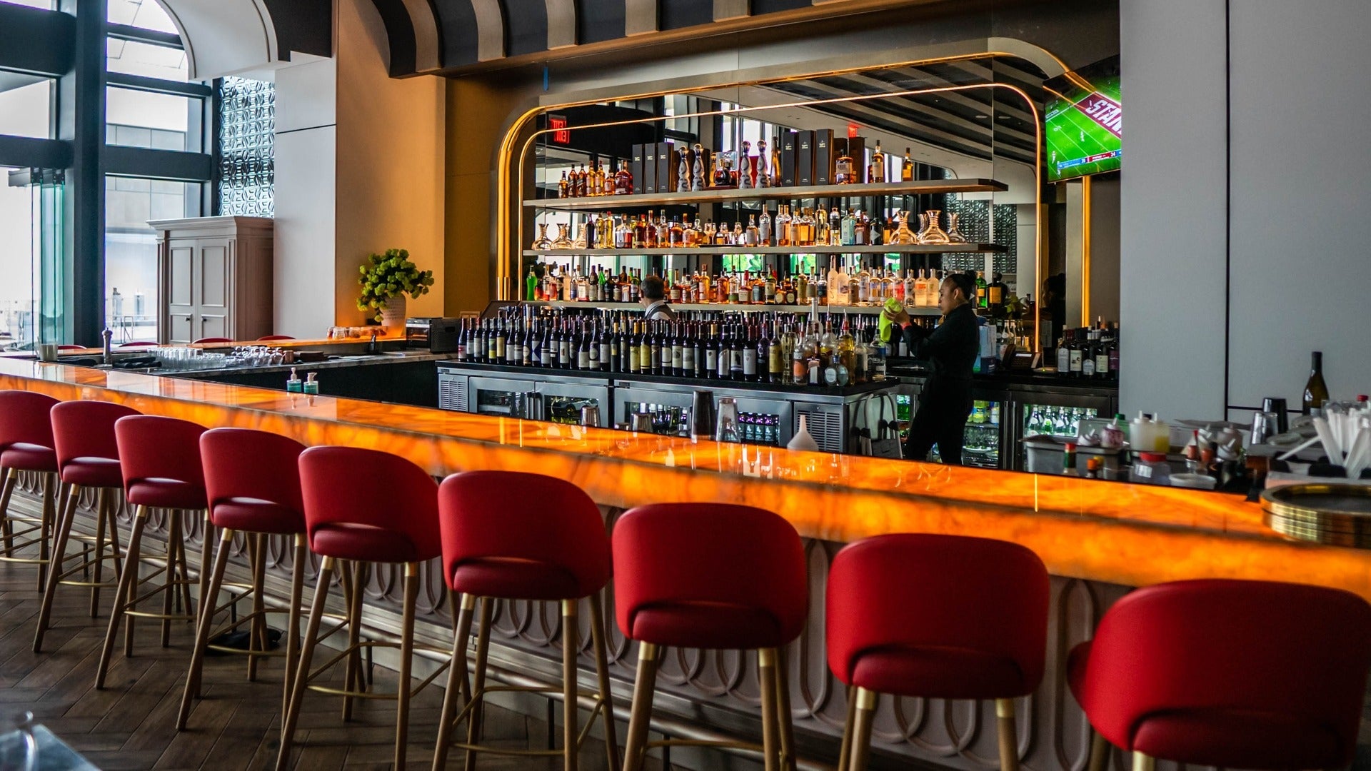 bar with bar chairs and alcohol in shelves at the back