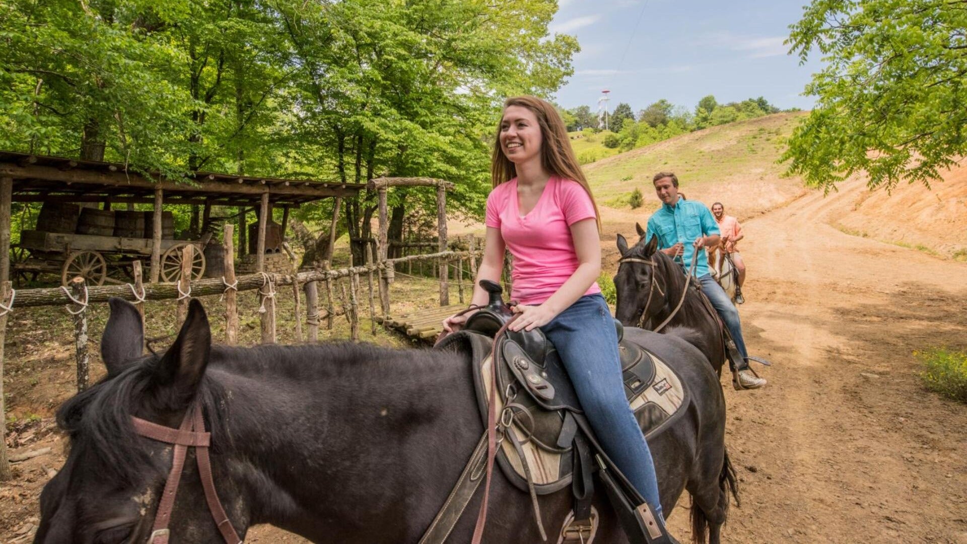 group of people riding horses, surrounded by trees