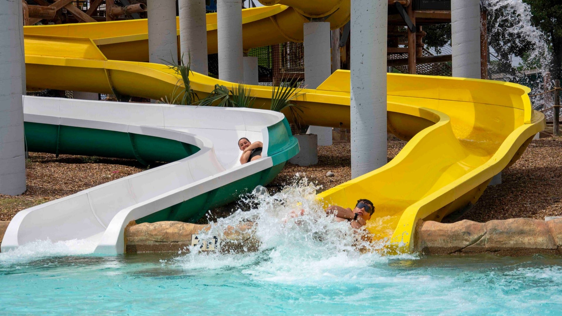 people going down slides in a pool