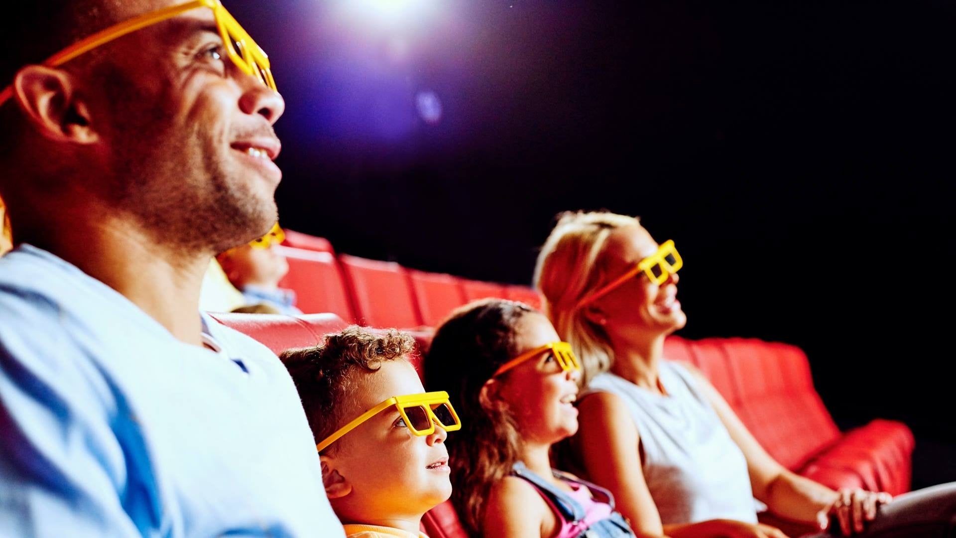 family sitting in a theater watching a movie wearing 3d glasses