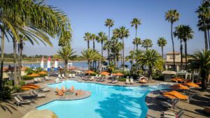 pool with pool cabanas and chairs, surrounded by palm trees