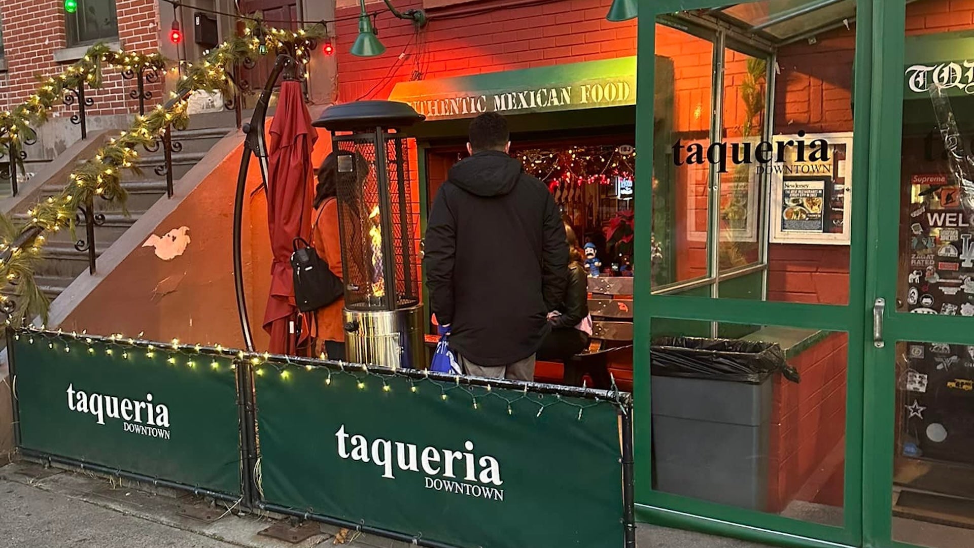 a man and a woman standing in front of a Mexican food restaurant