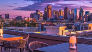 rooftop bar with tables, lamps, chairs, and view of city