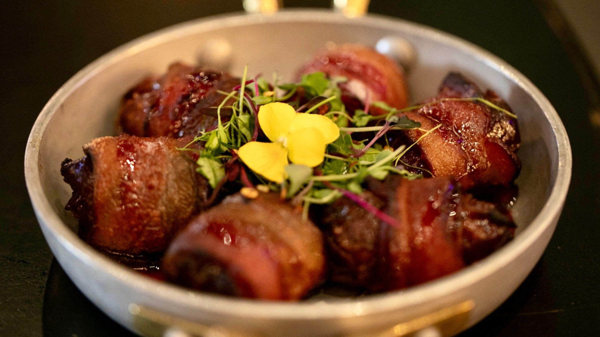 Bacon Wrapped Dates in a bowl with alfalfa sprouts